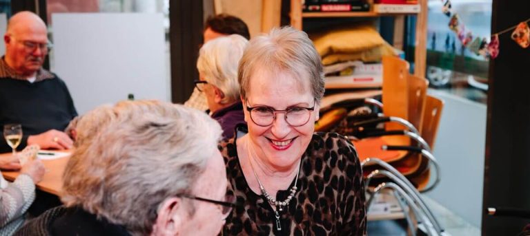 Twee vrouwen zitten te praten aan tafel over het project Samen Goud, ze zetten zich voor dit project in